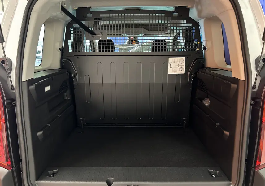 Vue arrière du coffre noir du Citroën Berlingo Multispace 2026 avec cloison de séparation métallique et sièges arrière visibles.