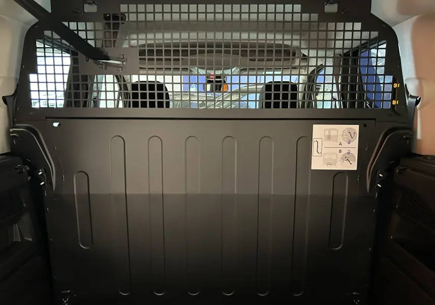 Vue intérieure arrière du Citroën Berlingo Multispace blanc Kaolin avec cloison de séparation métallique noire.