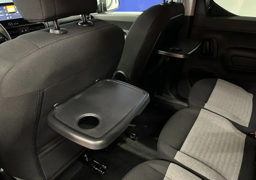 Vue intérieure arrière du Citroën Berlingo Multispace 2026 montrant les sièges tissu bicolores et tablettes rabattables noires.