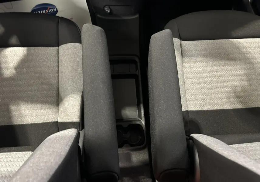 Vue rapprochée des sièges avant tissu gris et noir du Citroën Berlingo Multispace avec accoudoirs centraux relevés.