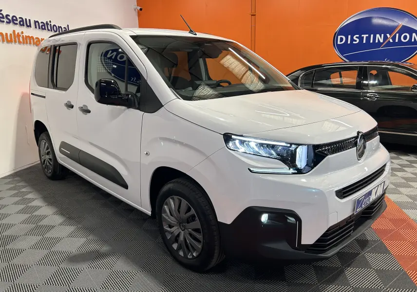 Citroën Berlingo Multispace blanc Kaolin en 3/4 avant droit, avec phares allumés et porte latérale coulissante visible.