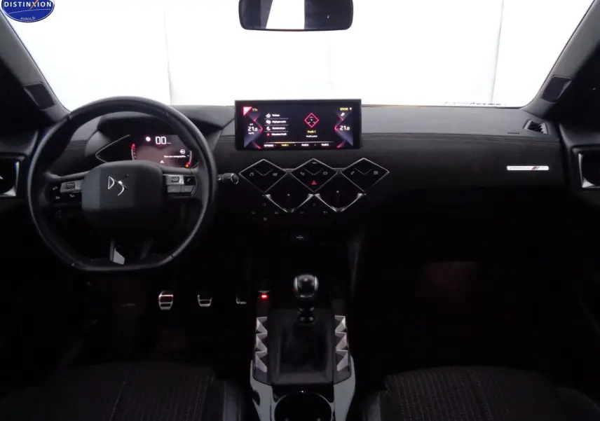 Vue intérieure avant du tableau de bord du DS3 Crossback blanc banquise, avec écran tactile et levier de vitesse manuel.
