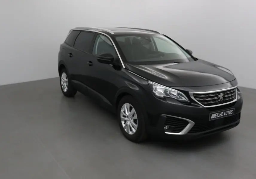 Peugeot 5008 noir vue 3/4 avant droit dans un studio, mettant en valeur sa calandre chromée et ses jantes argentées.