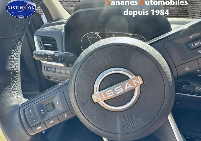 Vue rapprochée du volant Nissan du Qashqai 2023, avec commandes intégrées et tableau de bord en arrière-plan.
