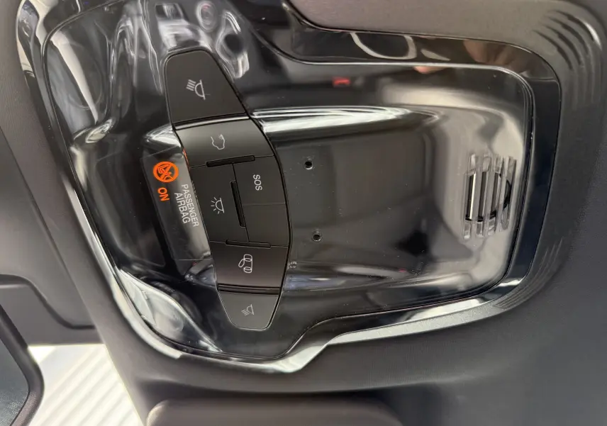 Vue en gros plan du panneau de commande intérieur noir brillant avec indicateur airbag passager activé de l'Alfa Romeo Stelvio blanc.