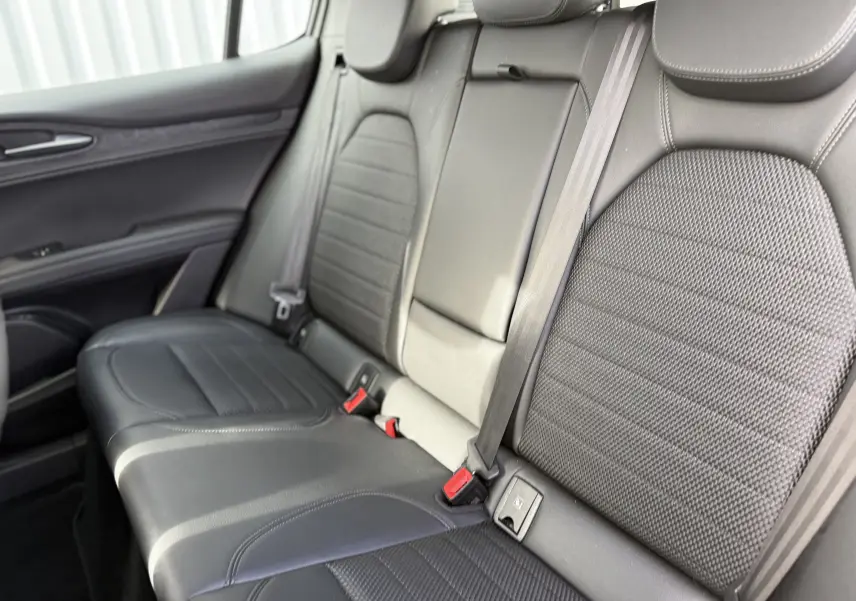 Vue latérale des sièges arrière en cuir noir de l'Alfa Romeo Stelvio 2023, soulignant les ceintures et finitions soignées.