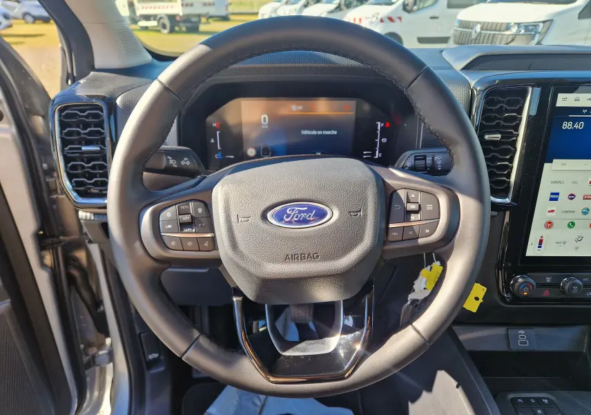 Vue rapprochée du volant multifonction du Ford Ranger Super Cabine 2026, avec tableau de bord numérique et écran tactile.