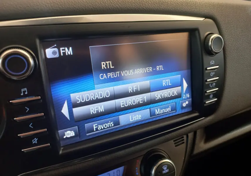 Écran tactile central affichant les stations FM dans l'habitacle noir d'une Toyota Yaris 2018 vue de face.