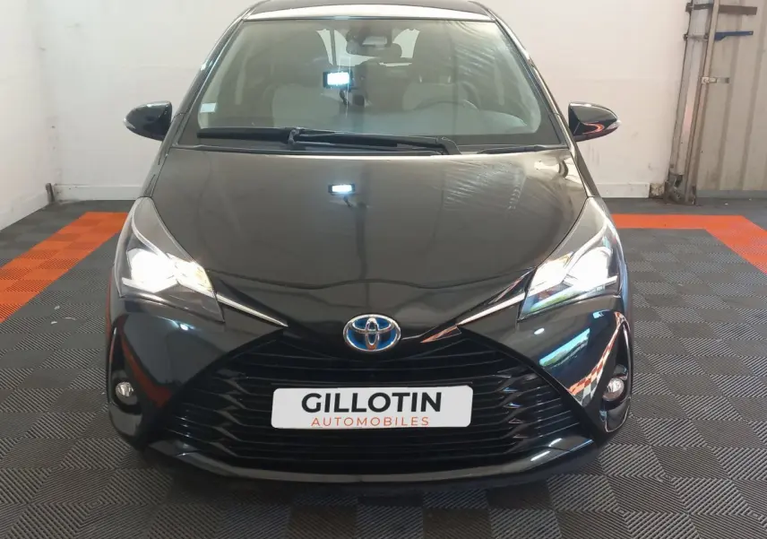 Vue frontale d'une Toyota Yaris noire 2018 avec phares allumés et calandre marquée en X.