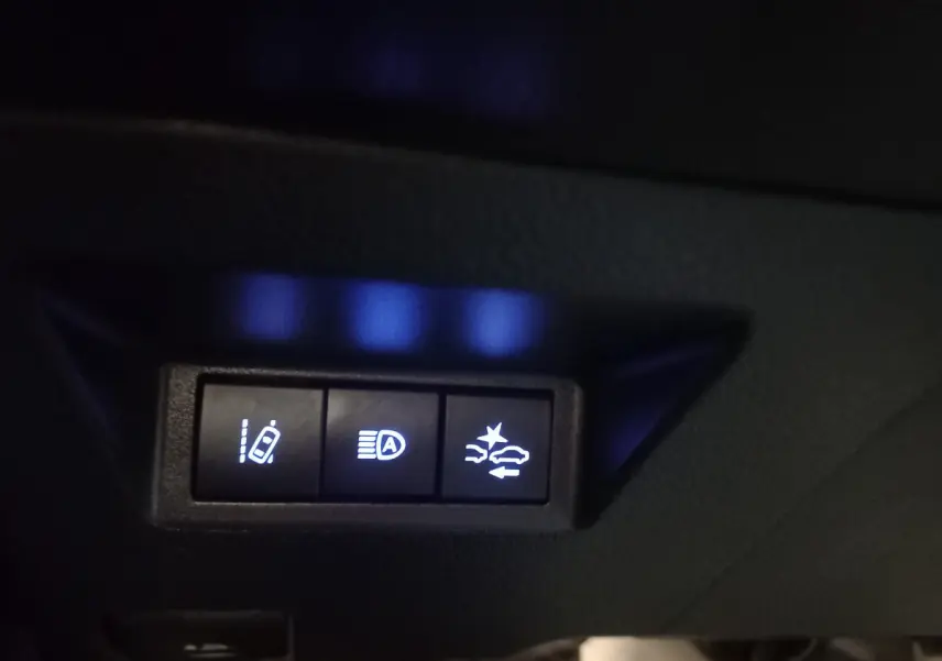 Gros plan sur les boutons de commande d'assistance à la conduite dans l'habitacle de la Toyota Yaris noire 2018.