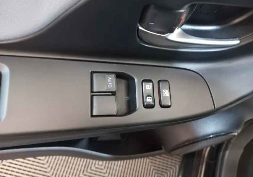 Gros plan sur les commandes de lève-vitres et verrouillage côté conducteur d'une Toyota Yaris noire de 2018.