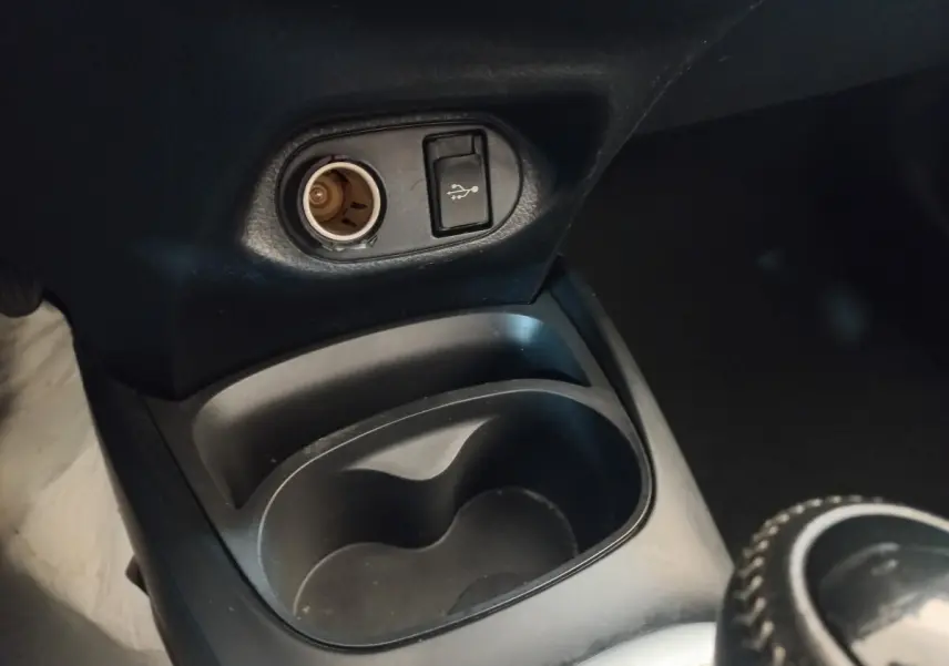 Prise 12V et port USB au-dessus des porte-gobelets dans l'habitacle noir de la Toyota Yaris hybride 2018.
