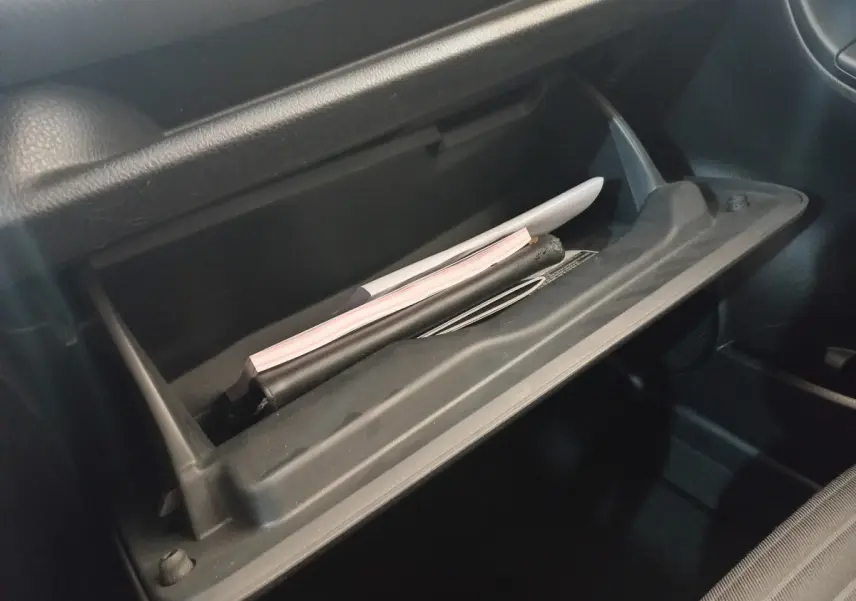 Gros plan sur la boîte à gants ouverte de la Toyota Yaris noire, montrant des documents à l'intérieur.
