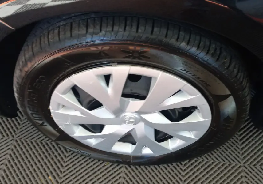 Gros plan sur la roue avant gauche de la Toyota Yaris noire, mettant en valeur la jante en alliage argenté au design moderne.