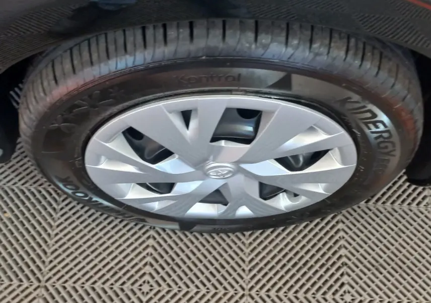 Gros plan sur la roue avant droite d'une Toyota Yaris noire, mettant en valeur la jante argentée et le pneu Hankook.