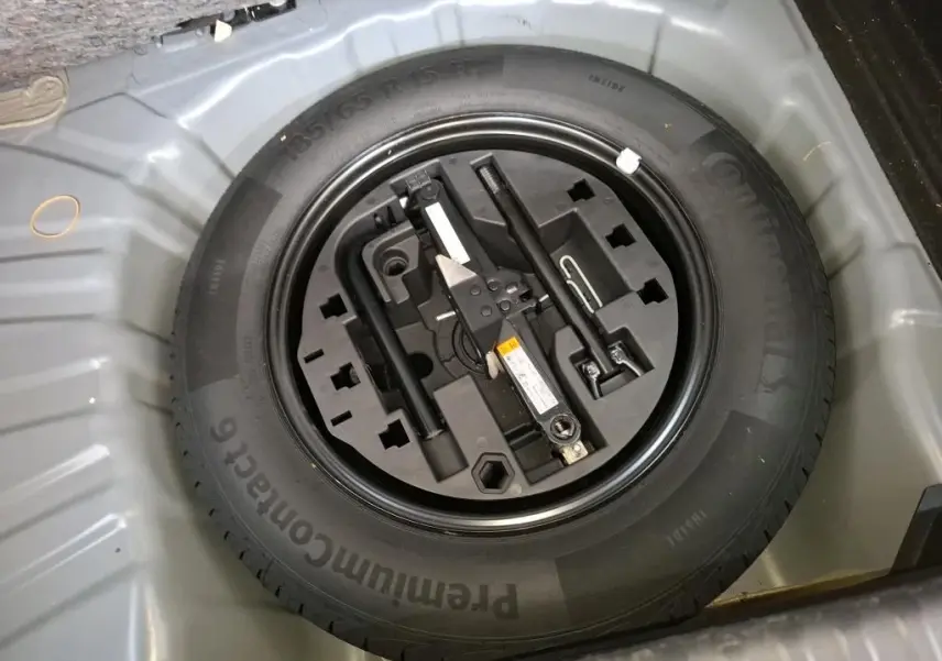 Gros plan sur la roue de secours et les outils de bord dans le coffre d'une Renault Clio Gris Titanium 2022.