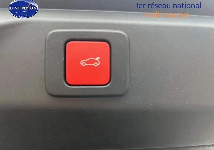 Bouton rouge d'ouverture électrique du coffre sur un Peugeot 3008 gris titane, vue en gros plan intérieur.