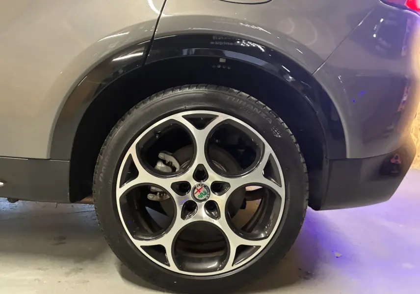 Vue arrière côté droit d'une Alfa Romeo Tonale gris foncé, mettant en valeur l'arche de roue et le feu arrière.