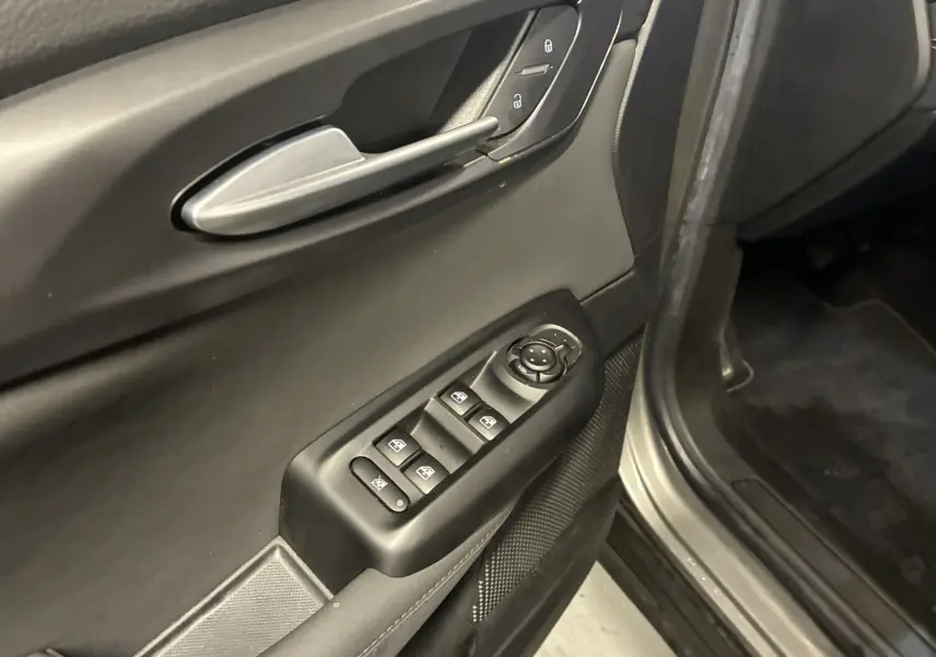 Gros plan sur la porte avant gauche de l'Alfa Romeo Tonale gris foncé, montrant les commandes des vitres et des rétroviseurs.