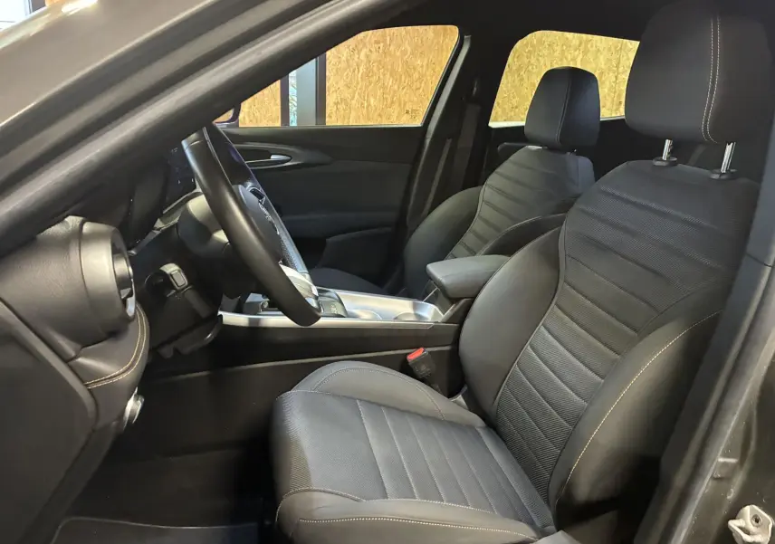 Vue intérieure côté conducteur de l'Alfa Romeo Tonale gris foncé 2023, sièges en cuir noir avec surpiqûres contrastées.