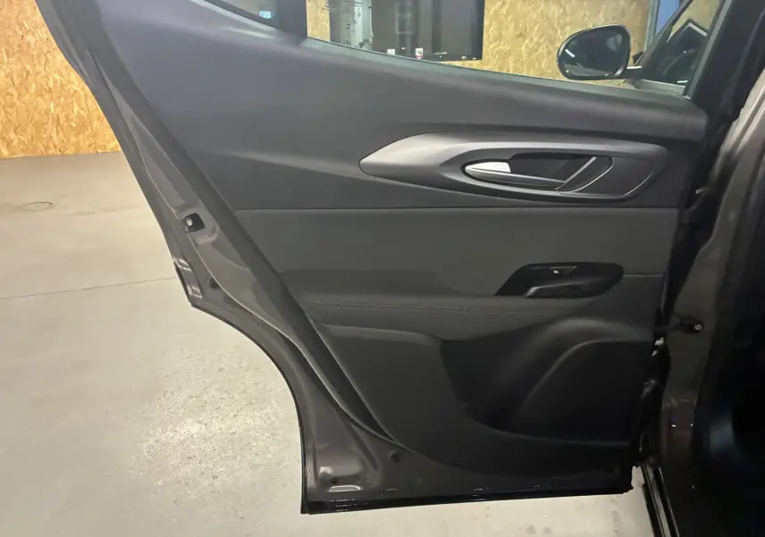 Vue intérieure de la porte arrière droite gris foncé de l'Alfa Romeo Tonale 1.3 PHEV 280 BVA TI avec poignée argentée et panneau noir.