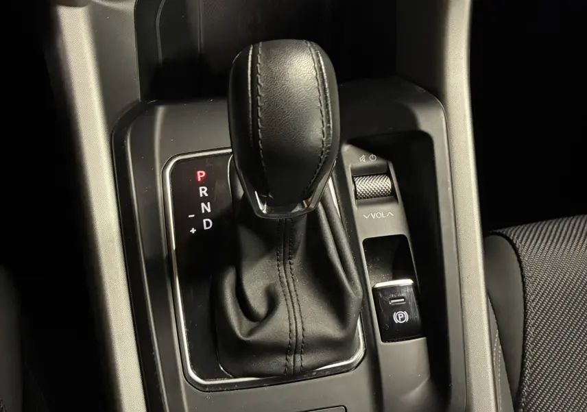 Gros plan sur la console centrale de l'Alfa Romeo Tonale 1.3 PHEV 280 BVA TI 2023, levier de vitesse cuir noir et commandes.