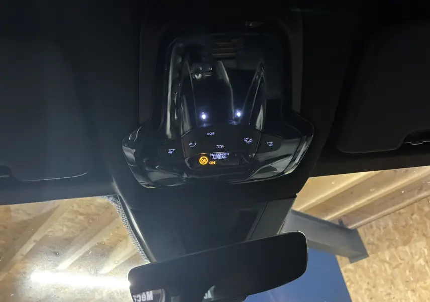 Vue intérieure du plafonnier noir de l'Alfa Romeo Tonale 1.3 PHEV 280 BVA TI avec commandes lumineuses et témoin airbag passager.