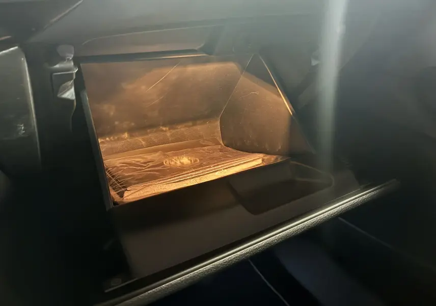 Intérieur de la boîte à gants éclairée de l'Alfa Romeo Tonale 1.3 PHEV 280 BVA TI, finition noire.