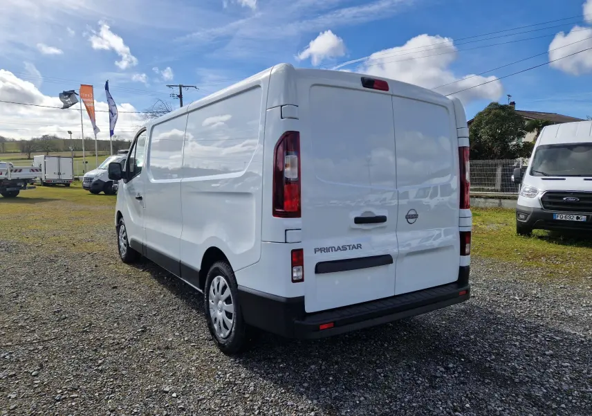 Vue 3/4 arrière droite du Nissan Primastar blanc 2025, fourgon utilitaire avec portes arrière pleines et jantes acier.