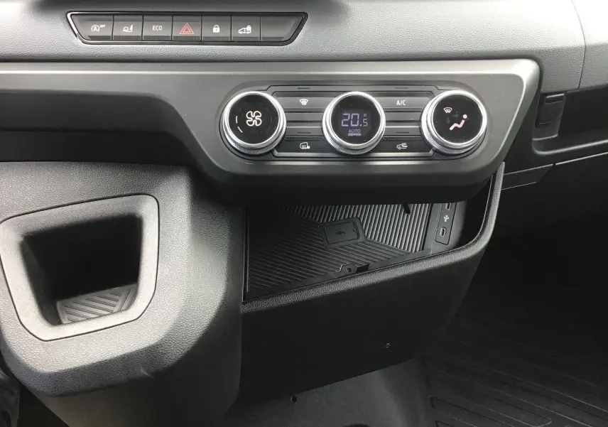 Vue rapprochée de la console centrale du Renault Master 2025 blanc, montrant les commandes de climatisation et un espace de rangement.