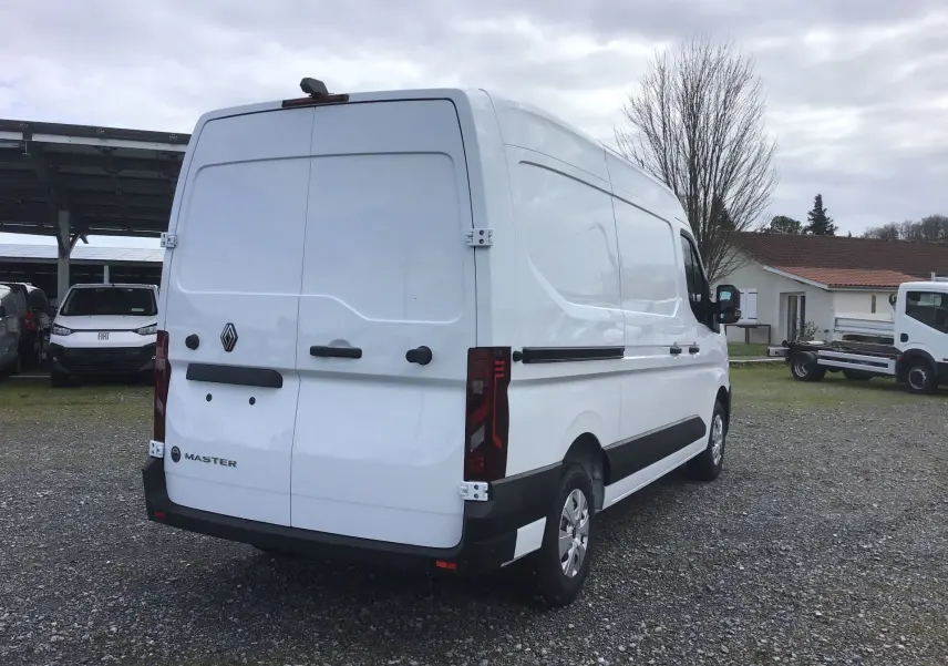 Vue 3/4 arrière droite d’un Renault Master blanc 2025, fourgon utilitaire avec portes arrière fermées et feux arrière verticaux.
