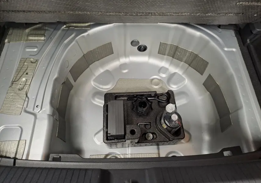 Coffre ouvert de Volkswagen Polo 2025, vue plongeante sur le logement de roue de secours en métal gris clair.