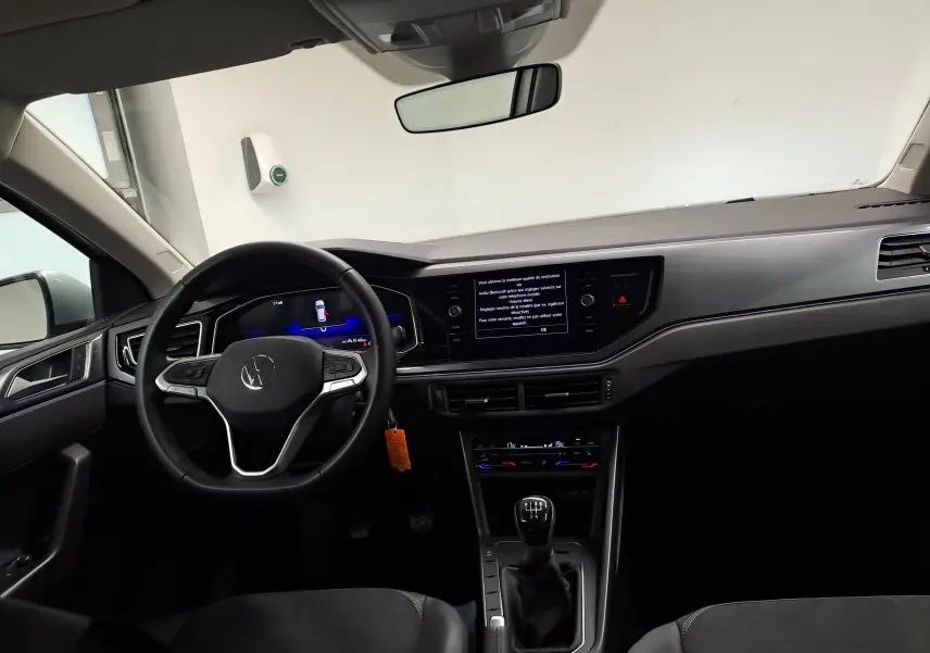 Vue intérieure avant de la Volkswagen Polo 2025 avec tableau de bord noir, volant multifonction et boîte manuelle.