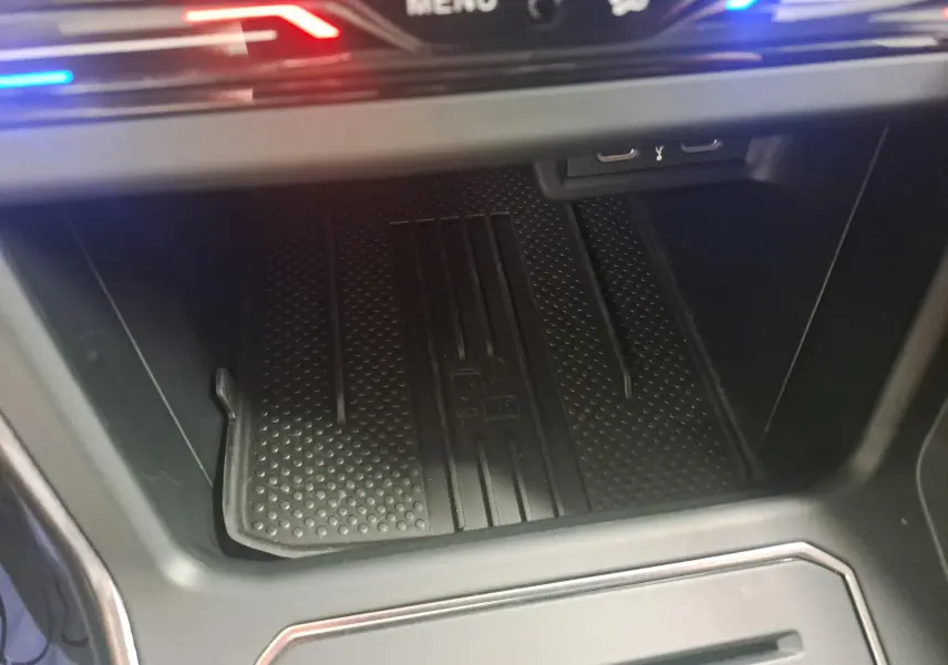 Gros plan sur la zone de rangement avant avec tapis antidérapant et éclairage LED rouge et bleu dans une Volkswagen Polo 2025.