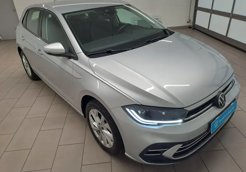 Vue 3/4 avant droite d'une Volkswagen Polo 2025 couleur reflet d'argent avec feux LED allumés en intérieur.