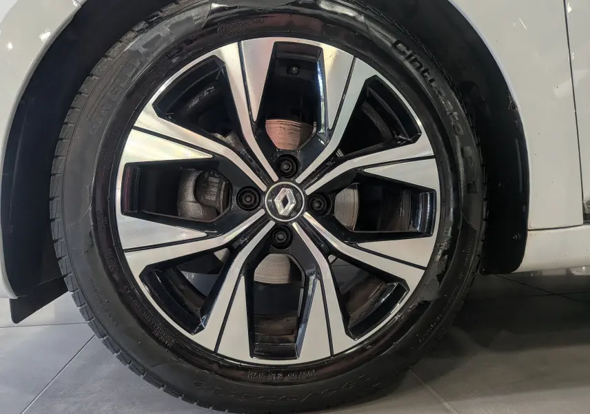 Gros plan sur la jante alliage bicolore d’une Renault Clio V Blanc Glacier, avec logo Renault au centre.