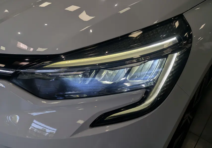 Gros plan sur le phare avant droit blanc glacier de la Renault Clio V TCe 100 CH GPL Evolution 2023 avec éclairage LED distinctif.