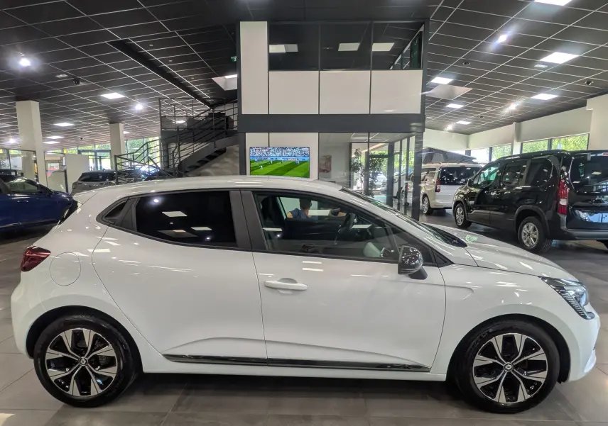 Renault Clio V TCe 100 CH GPL blanc glacier vue de profil côté gauche en intérieur avec jantes alliage bicolores.