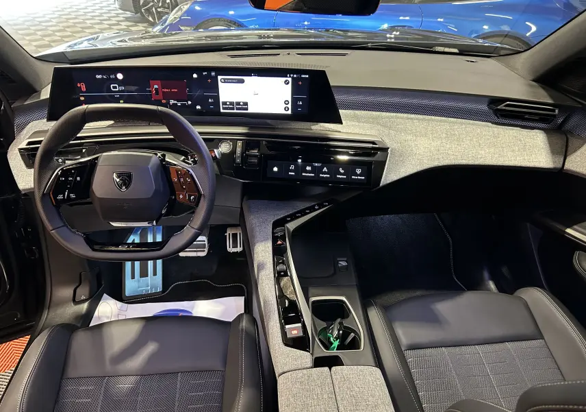 Vue intérieure avant du Peugeot 5008 Hybrid gris titane, mettant en valeur le tableau de bord numérique et le volant compact multifonction.
