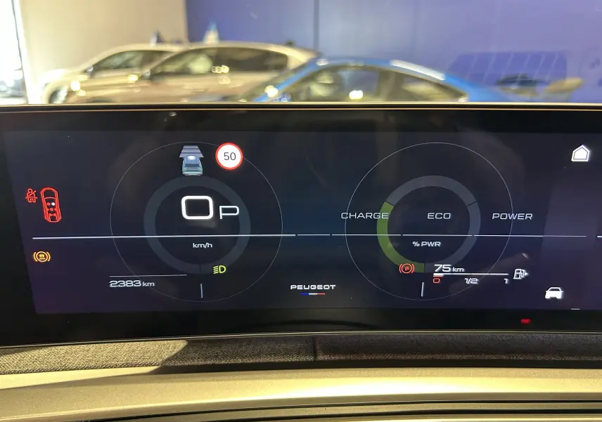 Tableau de bord numérique de Peugeot 5008 Hybrid gris titane, affichant vitesse, autonomie et mode éco en vue frontale.