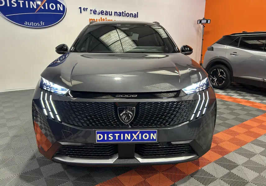 Vue de face du Peugeot 5008 Hybrid gris titane avec phares LED allumés et calandre noire texturée.