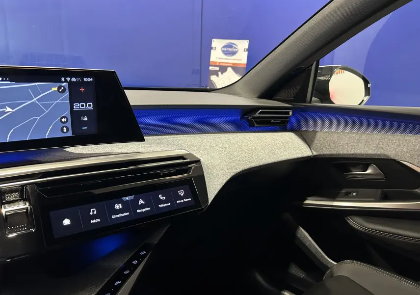 Vue intérieure côté passager du Peugeot 5008 Hybrid gris titane, avec éclairage d'ambiance bleu et écran tactile de navigation.