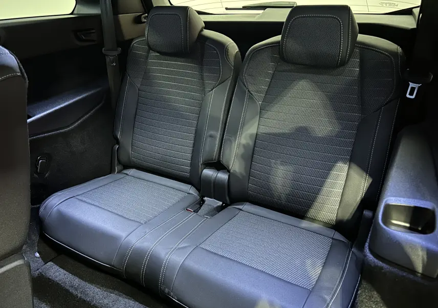 Vue rapprochée des sièges arrière en tissu noir et cuir sur Peugeot 5008 Hybrid 2025, ambiance intérieure soignée.