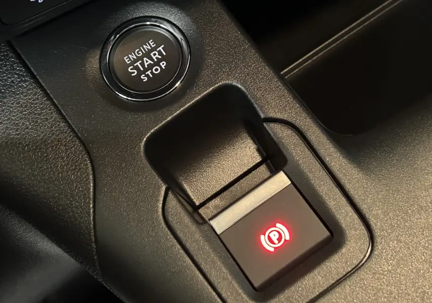 Gros plan sur le bouton de démarrage et le frein à main électrique rouge du tableau de bord noir du Citroën Berlingo Multispace.