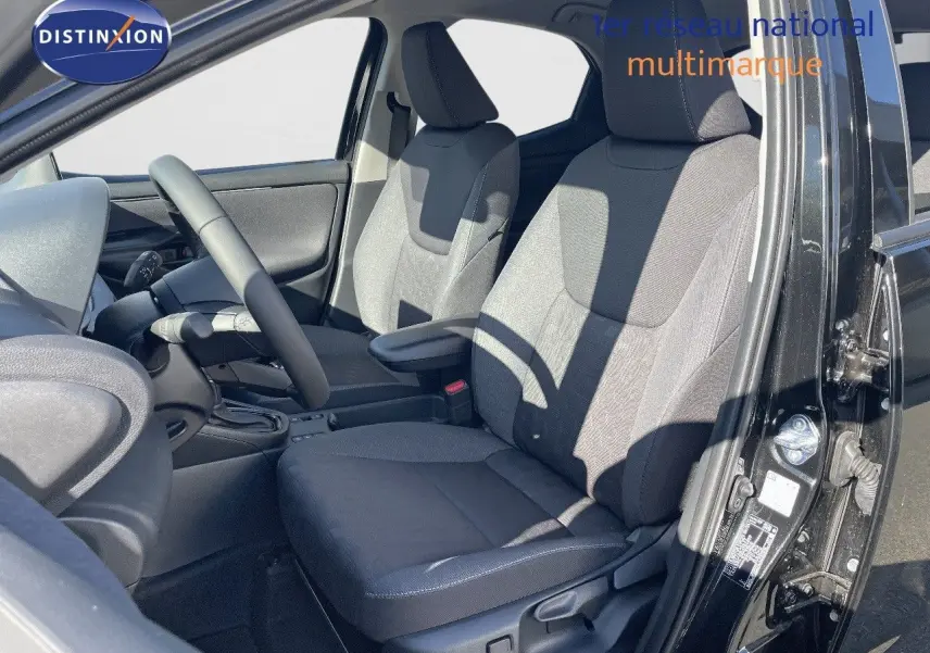 Vue intérieure côté conducteur de la Toyota Yaris Hybrid 116ch 2025 avec sièges tissu noir gris et volant noir.