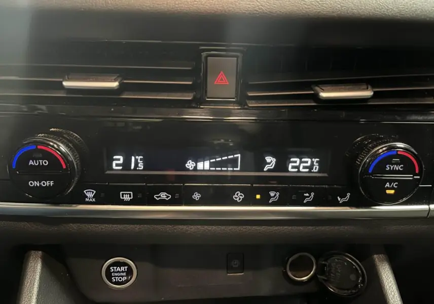 Vue rapprochée de la console centrale du Nissan Qashqai gris 2023, affichant la climatisation automatique bi-zone et le bouton Start/Stop.