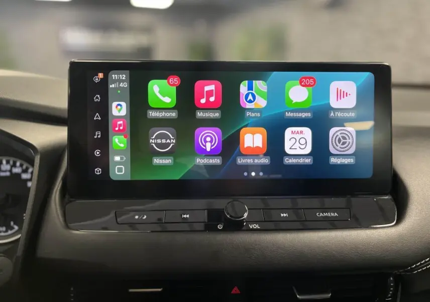 Écran tactile 9 pouces du Nissan Qashqai 2023 affichant Apple CarPlay sans fil et commandes sous l'écran.