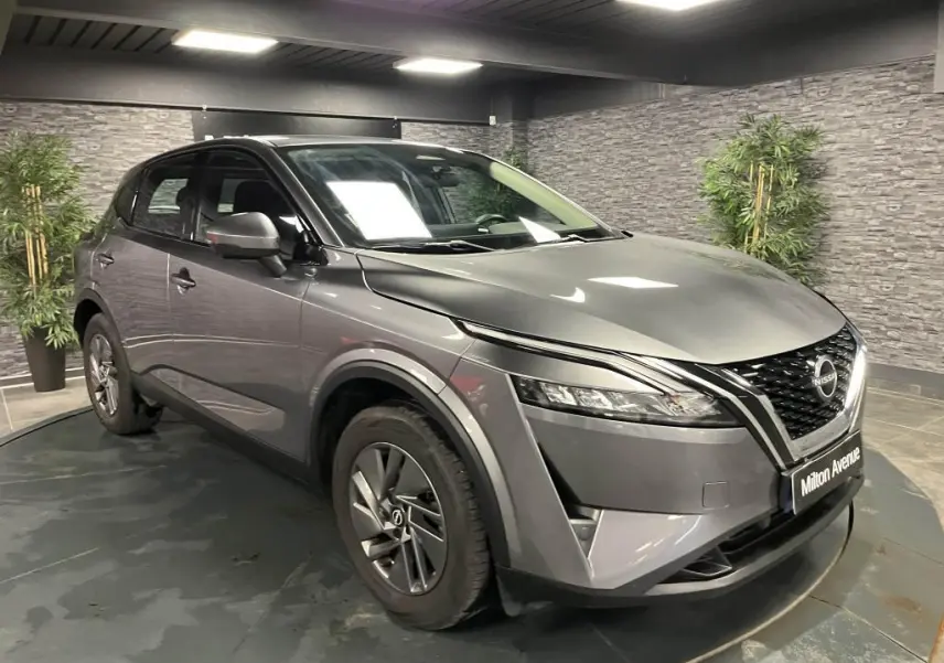 Nissan Qashqai gris 3/4 avant droit en intérieur, avec calandre noire et phares LED étirés.