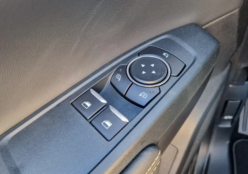 Gros plan sur les commandes de réglage des vitres et des rétroviseurs côté conducteur du Ford Ranger Super Cabine gris carbone.