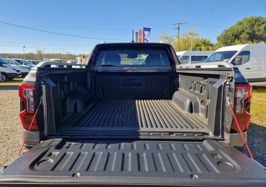 Vue arrière du Ford Ranger Super Cabine gris carbone avec benne ouverte et revêtement de protection noir.